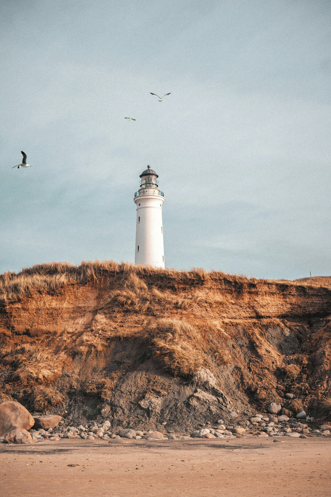 White lighthouse overlooking a calm beach