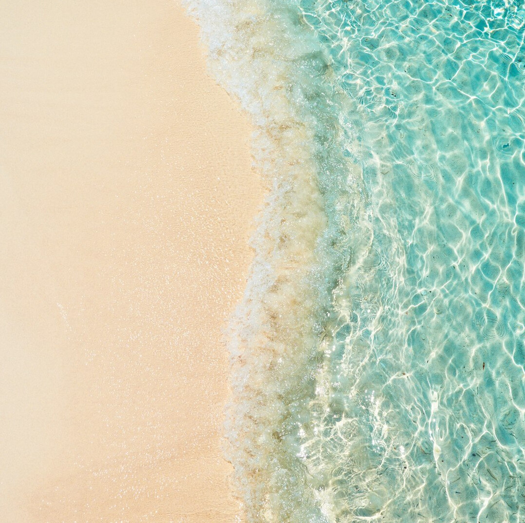 Aerial view of a golden sand coastline meeting turquoise ocean waves