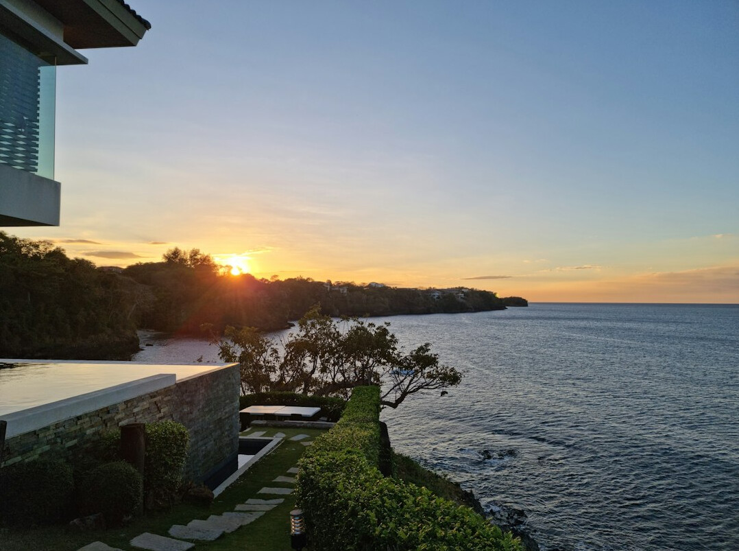 Contemporary concrete villa with an infinity pool overlooking the ocean at sunset
